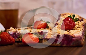 Wooden dark background of planks, white cloth, glasses with tea and homemade pie with cherries and strawberries. Delicious pastrie