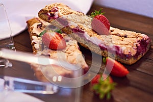 Wooden dark background of planks, white cloth, glasses with tea and homemade pie with cherries and strawberries. Delicious pastrie