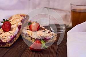 Wooden dark background of planks, white cloth, glasses with tea and homemade pie with cherries and strawberries. Delicious pastrie