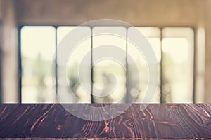 Wooden dark board empty table top on of blurred background. Perspective brown wood table over blur in coffee shop background - can