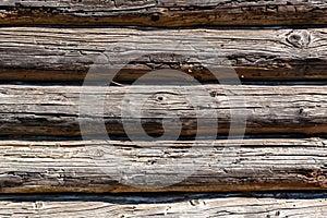 Wooden dark faded brown logs background with cracks and splits