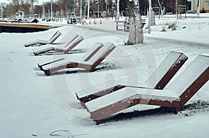 Wooden deck chairs, for relaxing on the river bank, powdered with fresh snow, no one