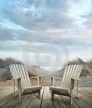 Wooden deck with chairs, sand dunes and ocean