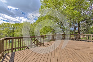 Wooden deck with cloudy skies and green trees