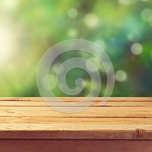 Wooden deck table with garden bokeh background. Ready for product display montage.