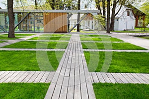 Wooden decking on a green bright lawn in a city park on a clear sunny day. Nature flora plant