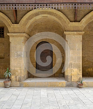 Wooden decorated door framed by arched bricks stone wall