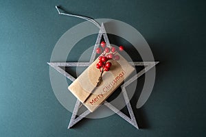 Wooden decorative silver star with empty note and berries on a green dark background, Christmas background