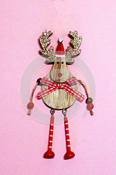 Wooden deer with golden shiny antlers in santa hat on pink background