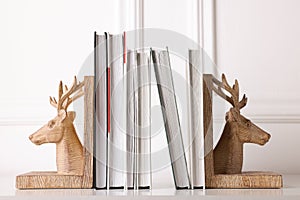 Wooden deer shaped bookends with books on table indoors photo