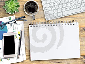 Wooden desk with blank notebook, Coffee cup,keyboard,smartphone,pencil and glasses