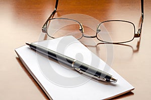 Wooden Desk with Notepad and Glasses