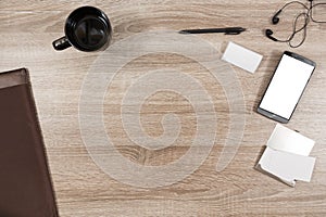 Wooden desk with smartphone, headphones, name tag, pen, black co