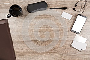 Wooden desk with smartphone, headphones, name tag, pen, coffee m