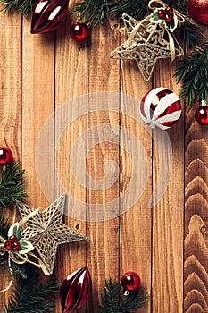 Wooden desk table background with Christmas decorations and fir tree branches on corners of frame. Christmas vertical banner