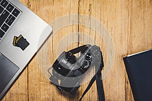 Wooden desk table with camera, laptop, memory cards and clipboard. photo