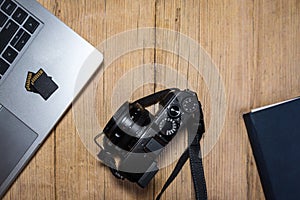 Wooden desk table with camera, laptop, memory cards and clipboard. photo