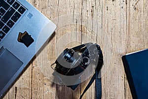 Wooden desk table with camera, laptop, memory cards and clipboard. photo