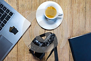 Wooden desk table with camera, laptop, memory cards, espresso cup and clipboard. photo