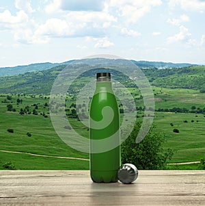 Wooden desk with thermos and landscape on background