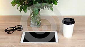 Wooden Desk. White tablet with black-rimmed glasses. White Cup of coffee