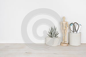 Wooden desktop with flower pot, human statuette and office supplies