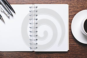 Wooden desktop with spiral diary and coffee