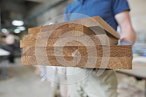 Wooden details in hands of male carpenter, woodworking industry