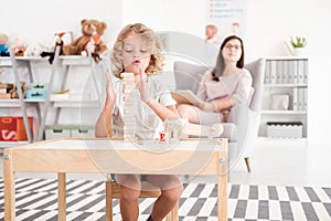 Wooden development props in the hands of a child during an educational therapy meeting with a pedagogue in a private medical offic