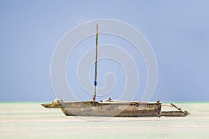 Wooden Dhow boat lying dry at low tide on a tropical beach