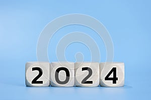 Wooden dice 2024 happy new year on blue background pastel black number