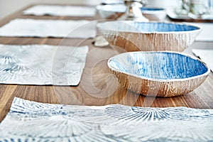 Wooden dinner table on massive legs with dishware in modern apartment. Close-up