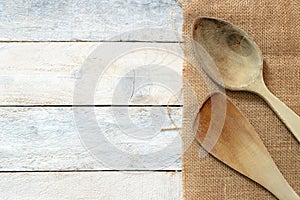 Wooden dipper kitchenware on a sack on a white wooden table