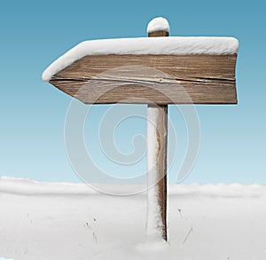 Wooden direction sign with less snow with sky on background