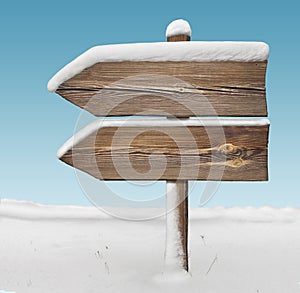 Wooden direction sign with less snow and sky bg. two_arrows-one_direction