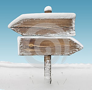 Wooden direction sign with snow and sky bg. two_arrows-opposite_directions