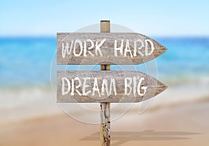 Wooden direction sign with work hard dream big
