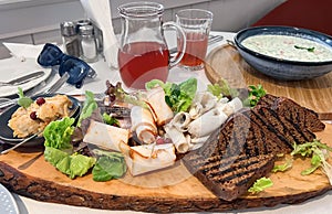 Wooden dish with freshly toasted black bread and various types of lightly salted lard