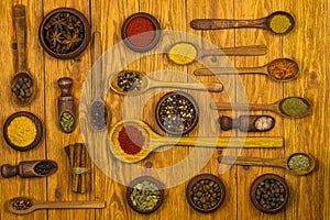 Wooden dishes with an assortment of spices on a light brown wooden background