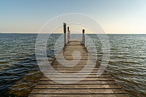 Wooden dock leading out into a calm blue ocean in evening light