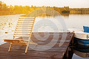Wooden dock with lounge chair on pier on the calm lake in the middle of the forest