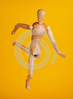 Wooden doll in football kick pose