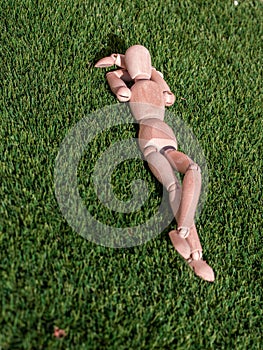 Wooden doll lying on the grass relaxed sunbathing