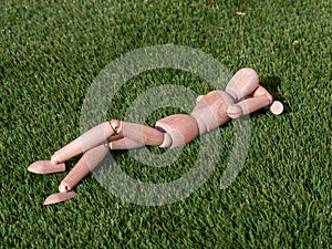 Wooden doll lying on the grass relaxed sunbathing