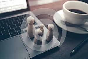 The wooden doll represents the employee of the company in workplace and document budget, calculator and coffee cup on the table.