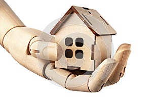 Wooden doll& x27;s hand holds a wooden toy house isolated on white. Real estate concept.