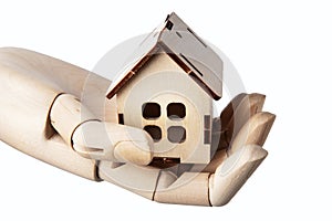 Wooden doll& x27;s hand holds a wooden toy house isolated on white. Real estate concept.