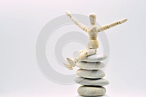 Wooden doll sitting on a pile of zen stones photo