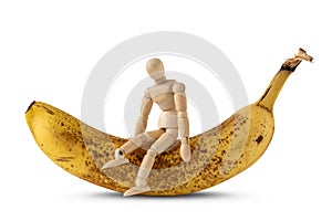 Wooden doll sitting on the ripe banana