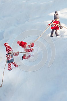 Wooden dolls on a snowy slope clinging to a rope